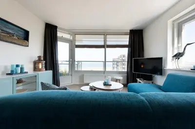a living room with a blue couch and a tv at Sterflat 99 in Egmond aan Zee