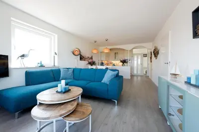 a living room with a blue couch and a table at Sterflat 99 in Egmond aan Zee
