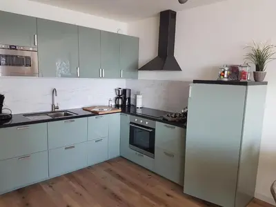 a kitchen with white cabinets and a stove top oven at Sterflat 103 in Egmond aan Zee