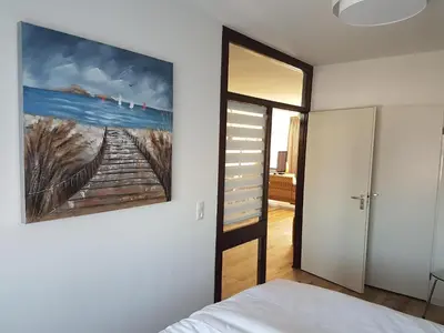a bedroom with a painting on the wall next to a bed at Sterflat 103 in Egmond aan Zee