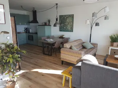 a living room with a couch and a table and a kitchen at Sterflat 103 in Egmond aan Zee