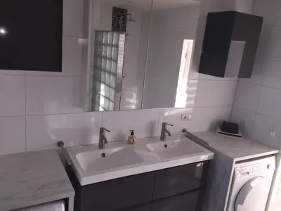 a white bathroom with a sink and a mirror at Sterflat 103 in Egmond aan Zee