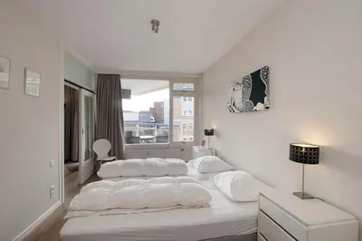 a bedroom with two beds with white sheets and a window at Sterflat 107 in Egmond aan Zee