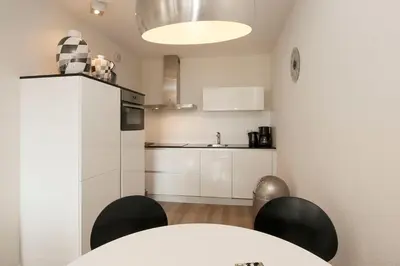 a kitchen with a table and chairs in a room at Sterflat 107 in Egmond aan Zee