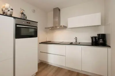 a kitchen with white cabinets and a sink at Sterflat 107 in Egmond aan Zee