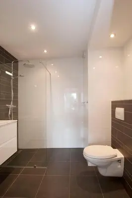 a bathroom with a toilet and a glass shower at Sterflat 107 in Egmond aan Zee