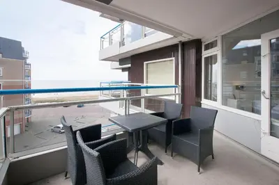a balcony with a table and chairs and a large window at Sterflat 107 in Egmond aan Zee