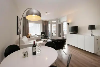 a living room with a white table and chairs and a living room at Sterflat 107 in Egmond aan Zee