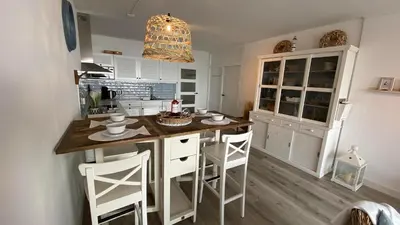 a kitchen with white cabinets and a island with bar stools at Sterflat 119 in Egmond aan Zee