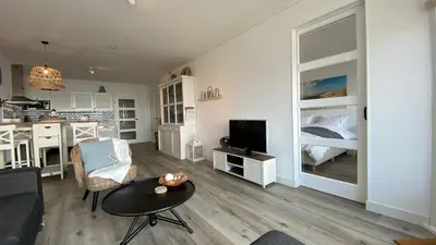 a living room with a kitchen and a room with a bed at Sterflat 119 in Egmond aan Zee