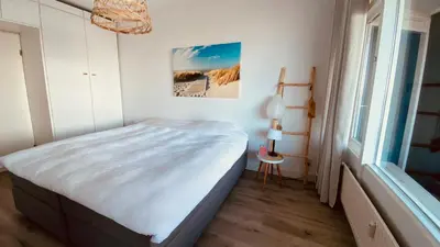 a bedroom with a bed in a room with a window at Sterflat 119 in Egmond aan Zee