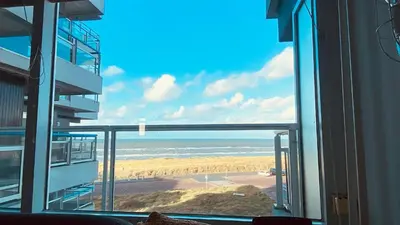 a view of a beach from a window of a building at Sterflat 119 in Egmond aan Zee