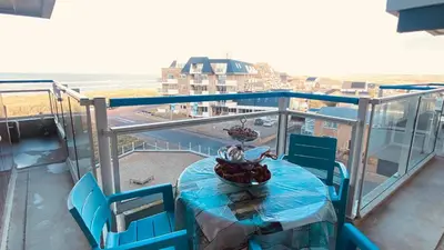 a table and chairs on a balcony with a view at Sterflat 119 in Egmond aan Zee