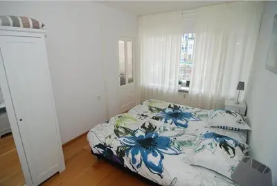 a bedroom with a bed with a blue floral bedspread at Sterflat 129 in Egmond aan Zee