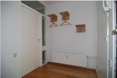 an empty room with white walls and wood floors at Sterflat 129 in Egmond aan Zee