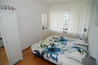 a bedroom with a bed with a blue floral bedspread at Sterflat 129 in Egmond aan Zee