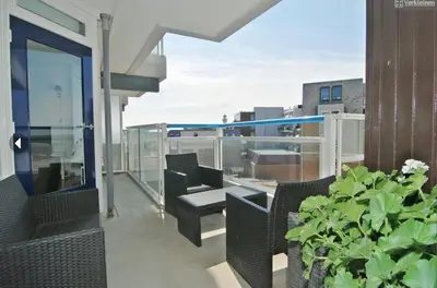 a balcony with chairs and a table and a plant at Sterflat 129 in Egmond aan Zee