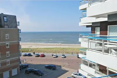 a view of a beach from a building with a parking lot at Sterflat 129 in Egmond aan Zee