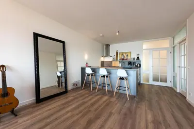 a room with a mirror and a counter with stools at Sterflat 147 in Egmond aan Zee