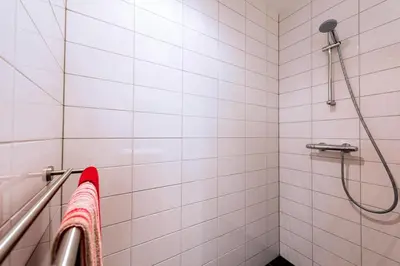 a bathroom with a shower with white tiles at Sterflat 147 in Egmond aan Zee