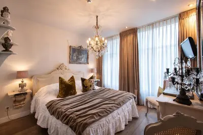 a bedroom with a large bed and a chandelier at l'Auberge Damhotel in Edam
