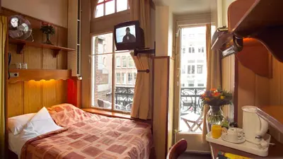 a bedroom with a bed and a tv and a window at Nadia Hotel in Amsterdam