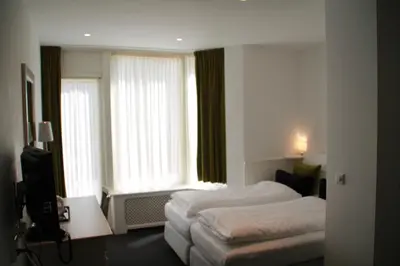 a hotel room with two beds and two windows at De Doelen in Leiden