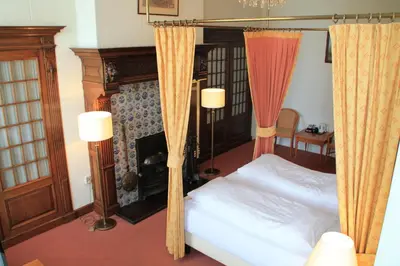 a bedroom with a canopy bed and a fireplace at De Doelen in Leiden