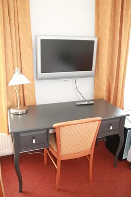 a desk with a television on a wall with a chair at De Doelen in Leiden