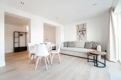 a white living room with a couch and a table at Studio Becke, with private parking in Zandvoort