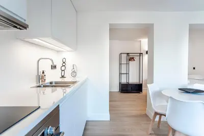 a white kitchen with a sink and a table at Studio Becke, with private parking in Zandvoort