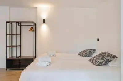 a white bed with two pillows and a mirror at Studio Becke, with private parking in Zandvoort