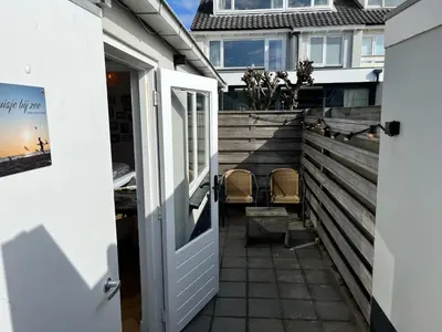 an open door to a patio with two chairs at Have a nice stay! - Huisje bij Zee gratis parkeren in Noordwijk aan Zee