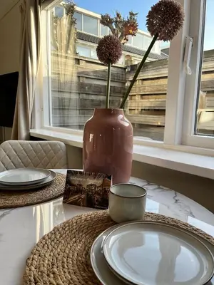 a table with a vase with flowers in a window at Have a nice stay! - Huisje bij Zee gratis parkeren in Noordwijk aan Zee