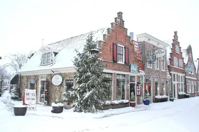 a snow covered street with a christmas tree in front of a building at Hotel & Restaurant De Fortuna in Edam
