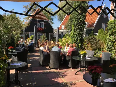 a group of people sitting at tables in a patio at Hotel & Restaurant De Fortuna in Edam