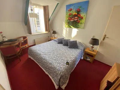 a bedroom with a bed and a painting on the wall at Hotel & Restaurant De Fortuna in Edam