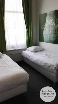 two beds in a room with green curtains at Rembrandt Square Hotel in Amsterdam