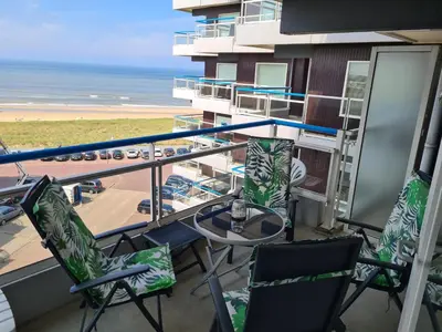 a balcony with chairs and a table and the ocean at Sterflat 151 in Egmond aan Zee