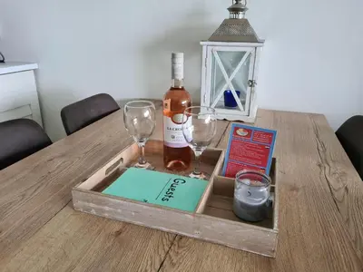a wooden tray with a bottle of wine and glasses on a table at Sterflat 151 in Egmond aan Zee