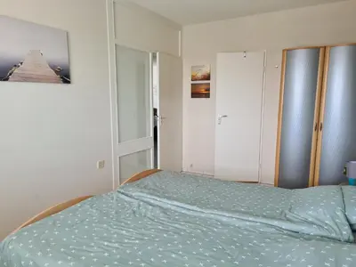 a bedroom with a bed with a green comforter at Sterflat 151 in Egmond aan Zee