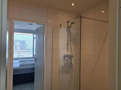 a bathroom with a shower with a glass door at Sterflat 151 in Egmond aan Zee