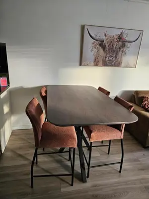 a dining room table with two chairs and a bull painting at Sterflat 157 in Egmond aan Zee
