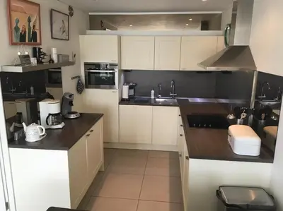 a kitchen with white cabinets and black counter tops at Sterflat 157 in Egmond aan Zee