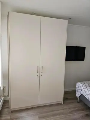 a large white cabinet in a bedroom with a bed at Sterflat 157 in Egmond aan Zee