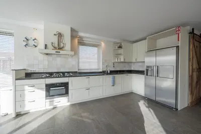 a kitchen with white cabinets and a stainless steel refrigerator at Meerzicht 71 - Perfectly suited for 6 persons in Uitgeest