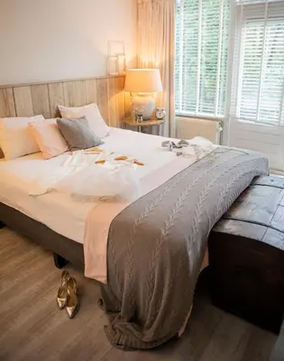 a bedroom with a large bed with shoes on it at Buitenplaats de Bergse Bossen in Driebergen