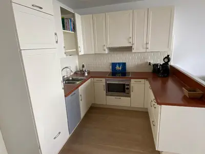 a small kitchen with white cabinets and a sink at Sterflat 173 in Egmond aan Zee
