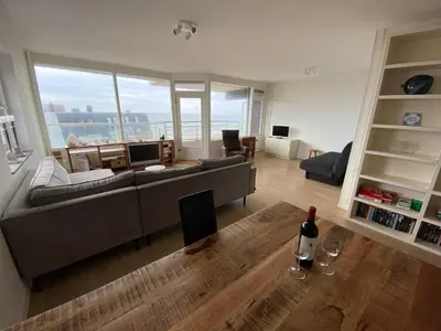 a living room with a couch and a bottle of wine at Sterflat 173 in Egmond aan Zee