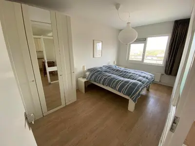 a bedroom with a bed and a large mirror at Sterflat 173 in Egmond aan Zee
